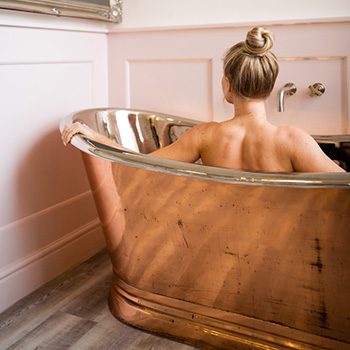 LAdy enoying a bath in a free-standing copper bath at Absoluxe Suites, Kirkby Lonsdale